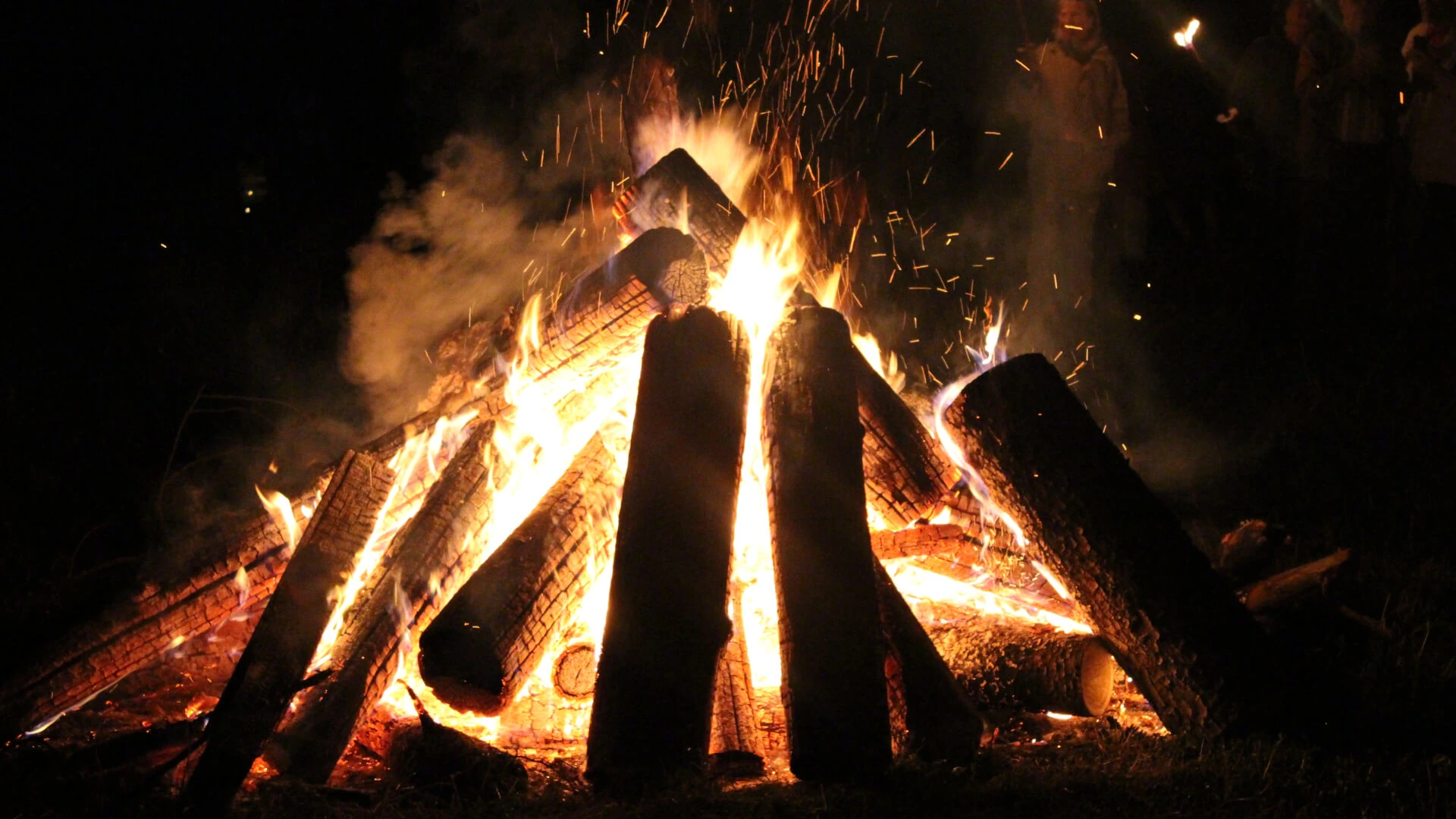 Brennendes aufgeschichtetes Holz bei Nacht als Symbol für Samhain