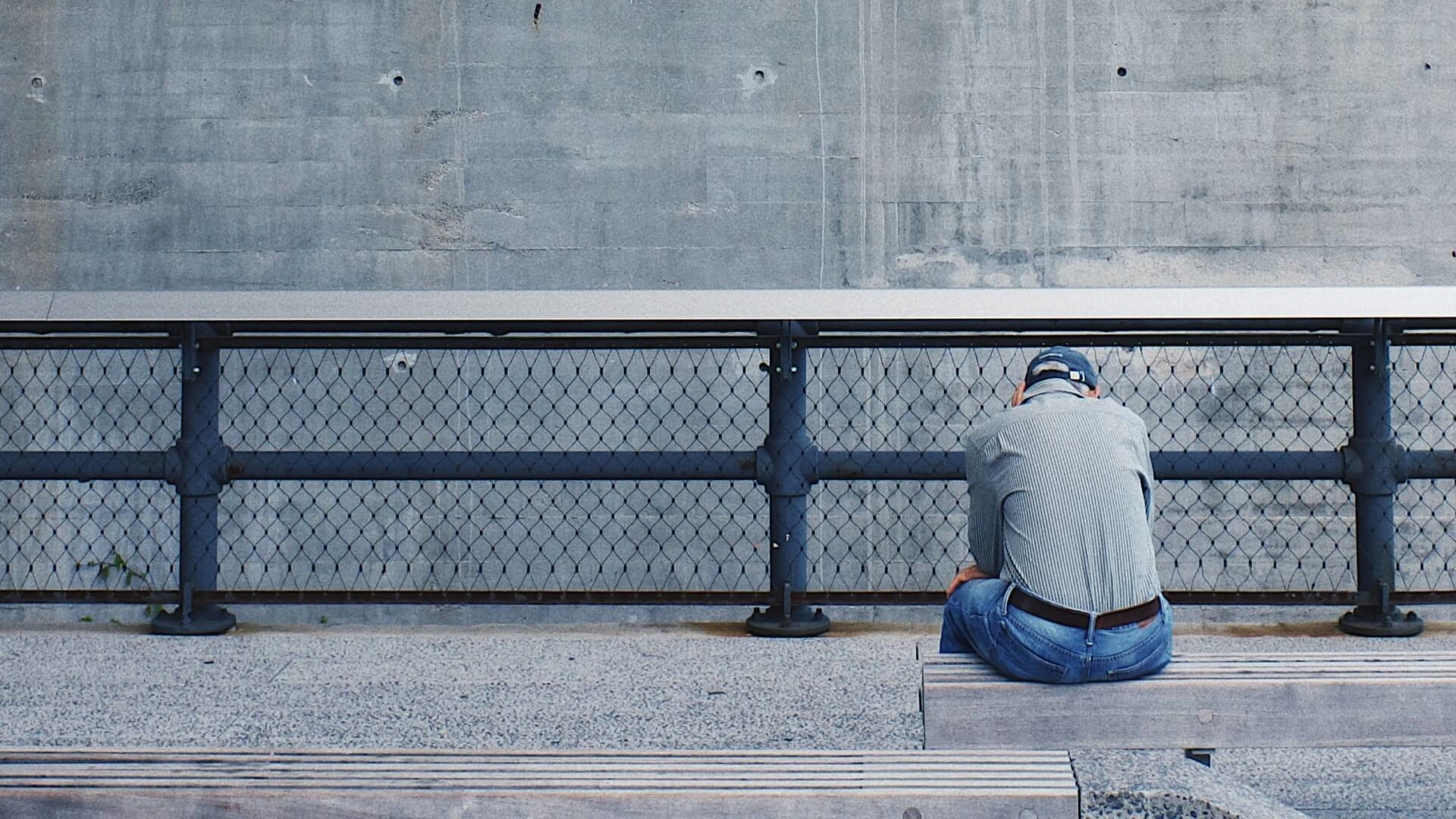 Bild zeigt seelische Blockaden in Form eines niedergekauerten Mannes vor einer Betonwand